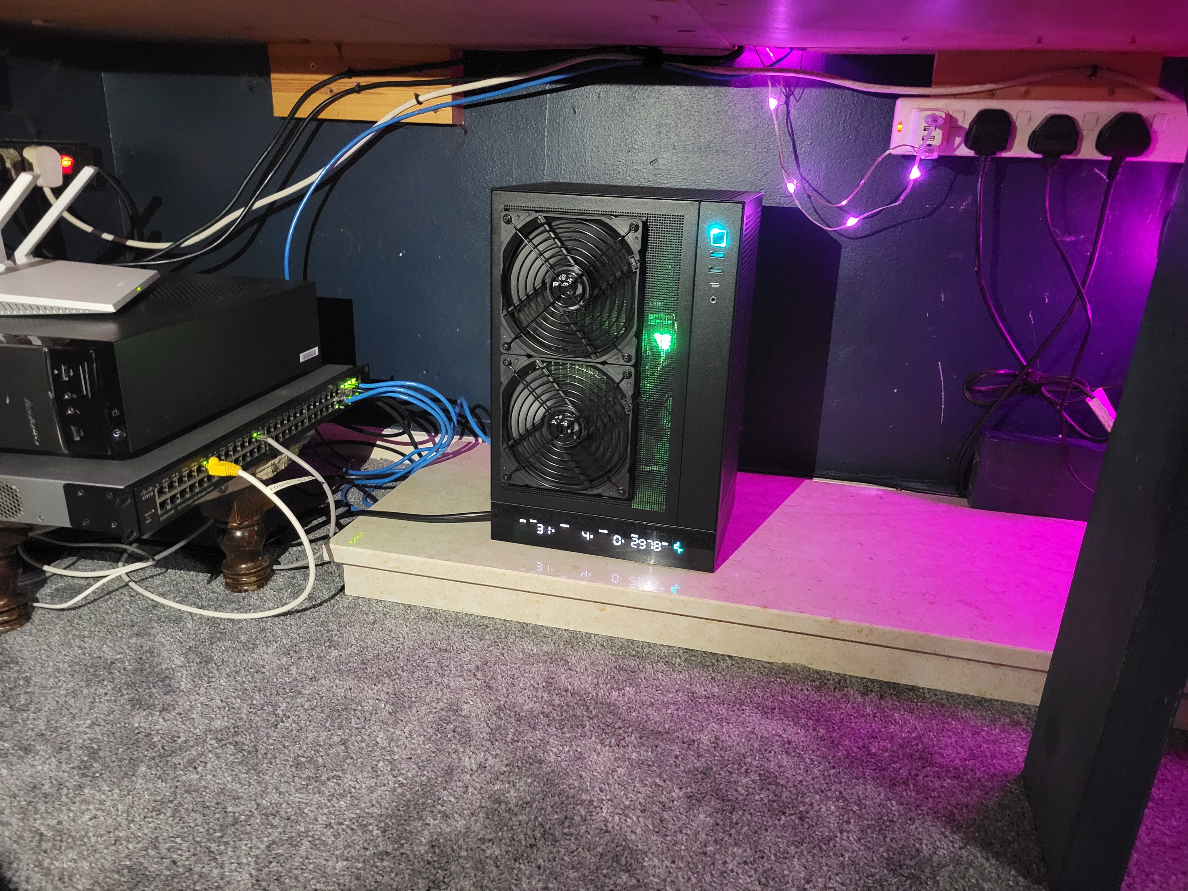 The workstation in situ in the workshop homelab, sitting next to network gear, cables routed in